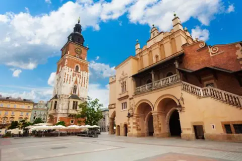 Wieża ratuszowa Kraków na Rynku Głównym, obok Sukiennic, pod błękitnym niebem.