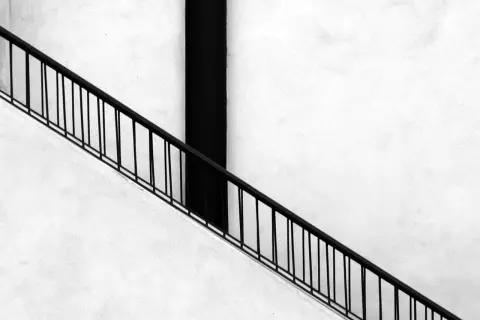 Ringhiera nera su muro bianco, un elemento essenziale per un montascale per anziani, agevolazioni per una vita più serena.