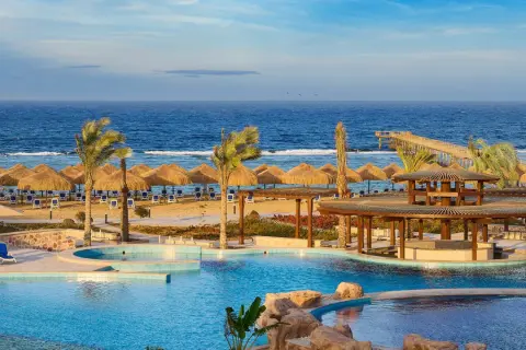 Relaks przy basenie i plaży z parasolami w hotelu Lazuli Marsa Alam. Błękitne morze i palmy tworzą rajski widok.
