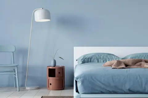 Ein hellblaues Schlafzimmer mit einem Bett, einem Stuhl und einem Nachttisch. Die schlafzimmer farbgestaltung wirkt beruhigend und modern.