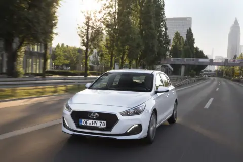 Biały Hyundai i30 1.6 benzyna jedzie autostradą w słoneczny dzień.