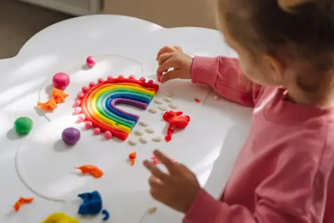 Dziecko tworzy tęczę z plasteliny. Świetne zabawy aktywizujące dla dzieci, rozwijające kreatywność i zdolności manualne.