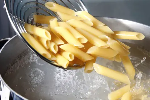 Penne vengono versate in acqua bollente. Il giusto quanto sale nella pasta è fondamentale per un sapore perfetto.