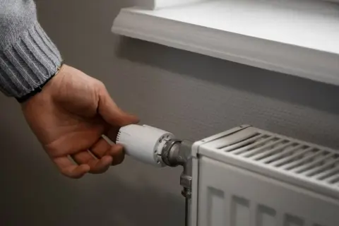 Dłoń reguluje zawór grzejnika, pokazując, jak zakręcić grzejnik bez termostatu.
