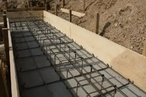 Siatka zbrojeniowa w drewnianej formie, gotowa na betonowanie. Widać, ile zbrojenia na fundamenty potrzeba do solidnej konstrukcji.