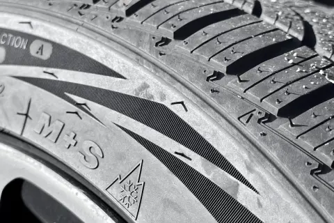 Gros plan sur un pneu 4 saisons, avec le symbole du flocon de neige et l'inscription M+S. Idéal pour affronter le verglas.