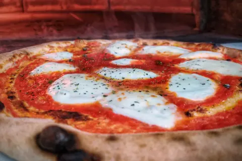 Gorąca pizza z ciągnącym się serem i sosem pomidorowym. Czy pizza jest ciężkostrawna? Zależy od składników i sposobu przygotowania.