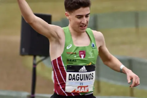 Le jeune athlète Etienne Daguinos, en pleine course, lève un bras victorieusement.