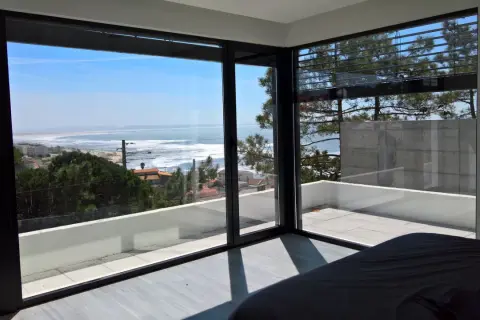 Ventana con vistas al mar, ideal para inspirar ideas para decorar ventanas. El interior minimalista contrasta con el paisaje exterior.