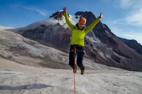 Radosny alpinista skacze na lodowcu pod Kazbekiem w Gruzji.