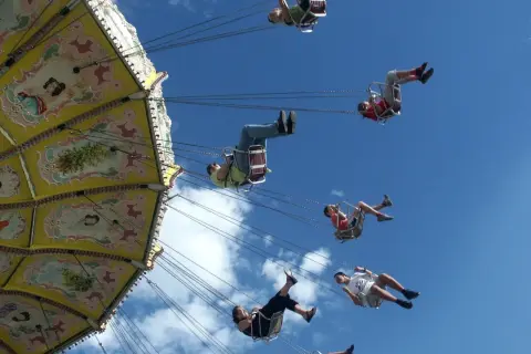 Flugkarussell auf dem Volksfest Gmund. Menschen schweben im Himmel, die bunte Kirmes dreht sich.