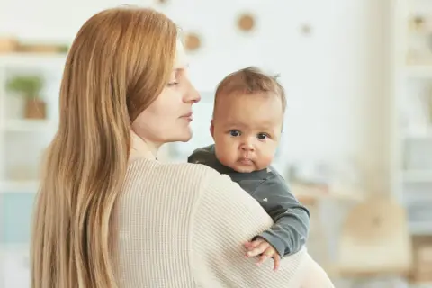 Mama tuli 4 miesięczne dziecko odchyla głowę do tyłu, patrząc z zaciekawieniem.