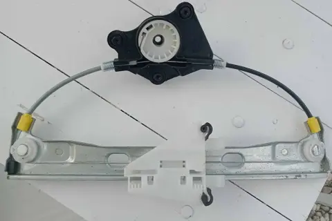 Mechanizm podnoszenia szyby, gotowy do wymiany. Składa się z metalowej szyny, linek i plastikowych elementów.