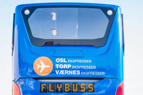 Niebieski Flybuss z napisem "OSL EKS<bos>. TORP EKS PRESEN", gotowy do podróży z lotniska Torp do centrum Oslo.
