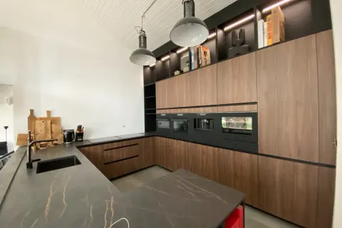 Cuisine moderne avec îlot central, plan de travail en marbre veiné, meubles en bois, électroménagers intégrés. Une belle idée aménagement cuisine.