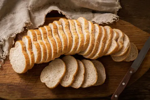 Czerstwy chleb pokrojony w kromki na desce. Świetny pomysł, co zrobić z czerstwego chleba, to grzanki lub bułka tarta.