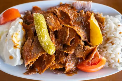 Pyszny kebab z mięsa mielonego, podany z ryżem, jogurtem, pomidorem i pikantną papryczką.