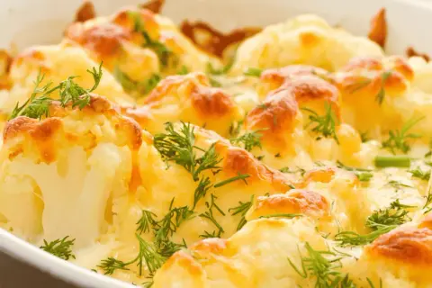 Coliflor al horno gratinada con queso y hierbas frescas, un plato reconfortante y delicioso.