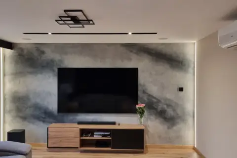 Nowoczesny salon z telewizorem na tle ściany z efektem betonu, jak zrobić tynk dekoracyjny.
