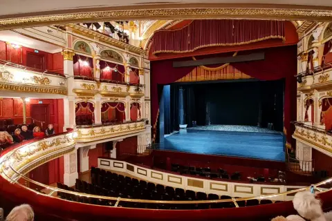 Prunkvoller Zuschauerraum im Oper Breslau, mit Logen, rotem Samt und goldener Verzierung.