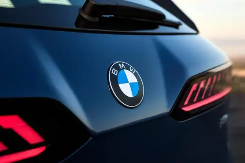 Nowe znaczki samochodowe BMW błyszczą na ciemnoniebieskim lakierze. Widoczne są charakterystyczne tylne światła.
