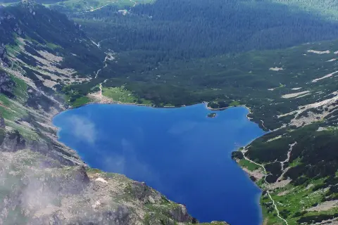 Widok z góry na **czarny staw gąsienicowy** otoczony skalistymi zboczami i gęstym lasem.