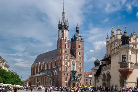 Majestatyczna Bazylika Mariacka w Krakowie góruje nad Rynkiem Głównym, gdzie tętni życie.