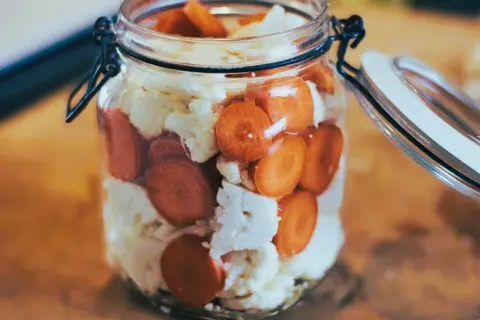 Ein Glas mit Karottenscheiben und Blumenkohl, bereit zum Blumenkohl fermentieren.