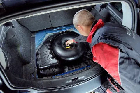 Mechanik sprawdza butlę LPG w bagażniku. Dowiedz się, ile kosztuje legalizacja butli LPG i jakie są formalności.