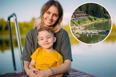 Uśmiechnięta mama z synkiem na pomoście. W tle jezioro z łódkami i domkami, idealne miejsce na wykorzystanie bonu turystycznego.