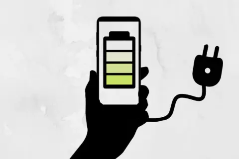 Mano sosteniendo un teléfono con batería a 3/4, conectado a un enchufe. ¡Un truco para el ahorro de batería!