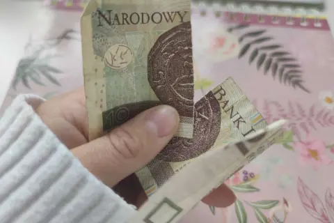 Dłoń trzyma sklejony banknot 10 zł. Zastanawiasz się, co zrobić ze sklejonym banknotem?