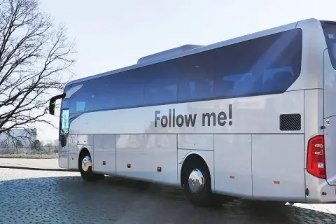 Autokar z napisem "Follow me!" czeka na pasażerów przy lotnisku w Koszalinie.