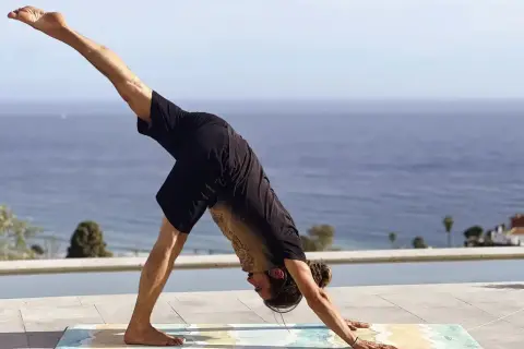 Hombre en postura de perro boca abajo, practicando yoga flow que es una secuencia fluida de posturas.