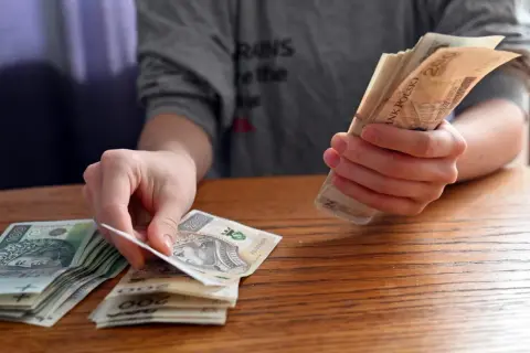 Dłonie liczą polskie banknoty. Zastanawiasz się, jakie dane o użytkownikach zbierają aplikacje pożyczkowe pod pretekstem loterii?