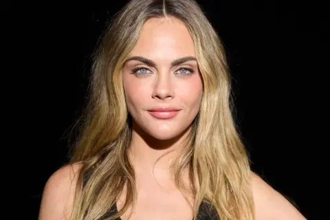 Cara Delevingne mit blondem, leicht plattem Haar und blauen Augen.