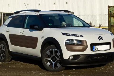 Biały Citroen Cactus z brązowymi wstawkami Airbump na drzwiach, zaparkowany na brudnym podjeździe.