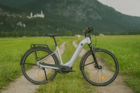 Szary rower elektryczny na drodze polnej z zamkiem w tle.