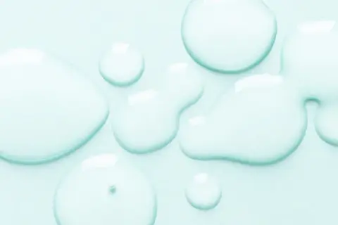 Gocce trasparenti su sfondo azzurro. Alcuni si chiedono se il cocamidopropyl betaine fa male, ma questa immagine mostra solo liquidi puri.