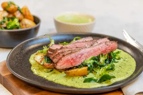Skivad flankstek med perfekt flankstek temp, serverad med rostade potatisar och en krämig örtsås.