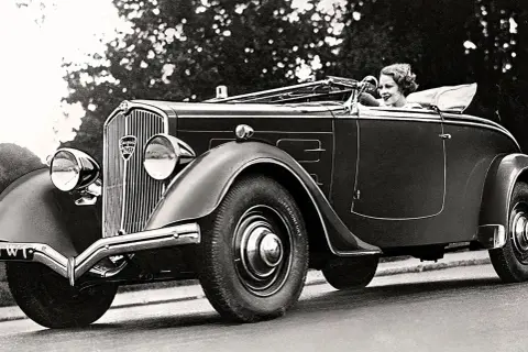 En kvinna kör en elegant cabriolet, ett exempel på gamla bilmodeller från 1930-talet.