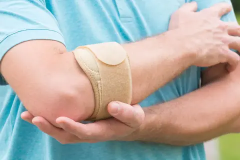 Mann mit Bandage am Ellenbogen, um den **Tennisellenbogen** zu lindern.