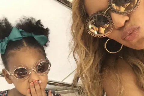 Mała córka Beyoncé w okularach w kształcie kwiatków i zielonej kokardce, obok mamy w okularach z ozdobnymi oprawkami.