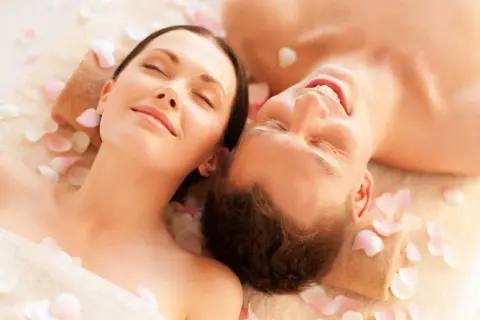 Para spędza relaksujący dzień w spa, leżąc wśród płatków róż.