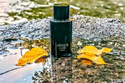 Elegancki flakon Armani Code Parfum 125ml, otoczony jesiennymi liśćmi i wodą, emanuje luksusem.