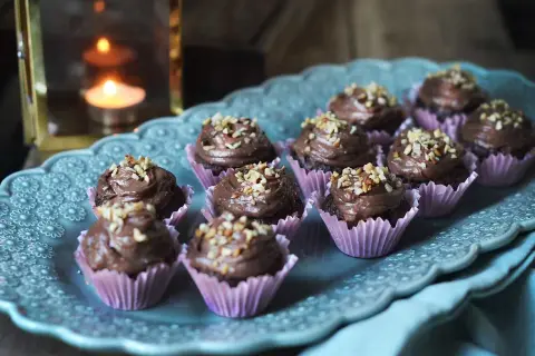 Mini cupcakes choklad med krämig frosting och hackade nötter, serverade på ett vackert fat.