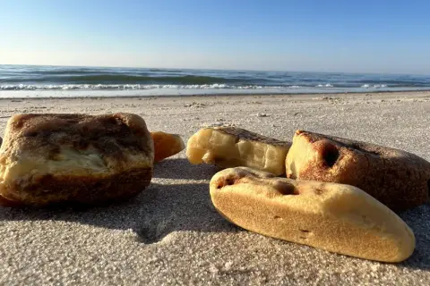 Kilka kawałków bursztynu leży na piaszczystej plaży. Warto wiedzieć, jak rozpoznać bursztyn na plaży, by cieszyć się skarbami Bałtyku.