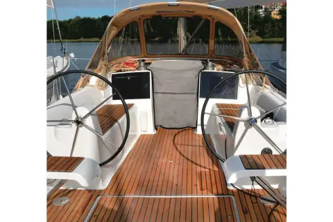 Il ponte di uno yacht con due timoni, un tendalino e un boccaporto, pronto per la navigazione.