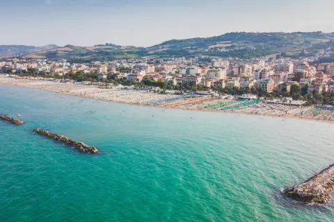 Vista aerea di San Benedetto del Tronto, con il suo lungomare affollato di ombrelloni colorati e il mare turchese.