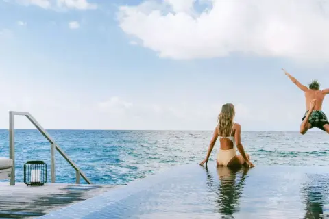 Ein Mann springt ins Meer, während eine Frau zusieht. Perfekte tschechien urlaub tipps für sonnige Tage am Wasser.